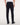 Rear view of a person wearing 7 For All Mankind Slimmy Jeans, Blue Black, a white shirt, and black shoes against a plain light background.