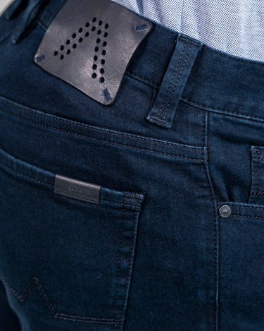 A close-up image of the back pocket area of a pair of Alberto Pipe Dual FX Jeans, Dark Blue showing the brand tag and a small decorative element.