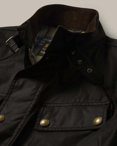 Close-up of a Belstaff Trialmaster Waxed Jacket, Black with a brown corduroy collar, brass snap buttons, and a strap detail on the shoulder.