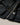 Close-up of a dark navy waxed cotton jacket with brass-toned snap buttons, a belt buckle detail, and a striped plaid lining with a visible Barbour logo patch.