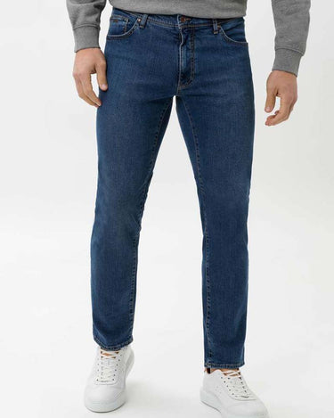 Person wearing Brax Cadiz Straight Fit Jeans, Blue and white sneakers on a white background