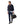 A man wearing a R.M. Williams Rydal Padded Gilet, Navyover a light blue button-down shirt, paired with dark blue jeans and black leather dress shoes, holding a black leather duffel bag with gold zippers. The photo is taken against a solid white background.