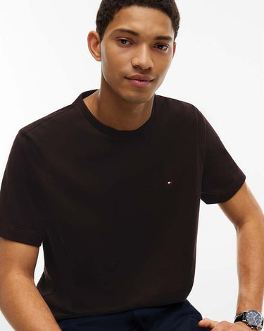 A man wearing a Tommy Hilfiger Flag Cotton T-Shirt, Brownwith a small Tommy Hilfiger flag logo on the left chest, photographed against a clean white background.