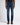 A model from the waist down wearing dark 7 For All Mankind Slimmy Jeans, Dark Blue, a black shirt, and brown leather shoes, standing against a light gray studio background.