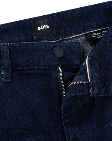 Close-up of BOSS Delaware Slim Fit Jeans in Navy showing the waistband, button closure, belt loops, front zip pocket, and interior labels including BOSS and DELAWARD.