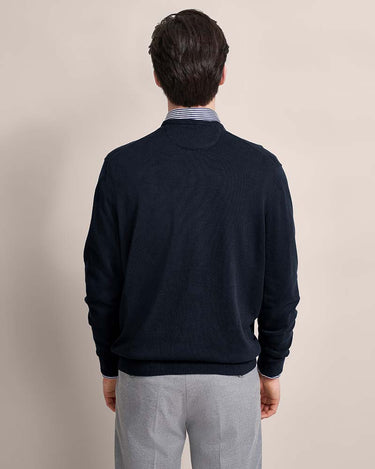 Man wearing a Bugatti V Neck Jumper, Navy over a striped shirt with a beige background