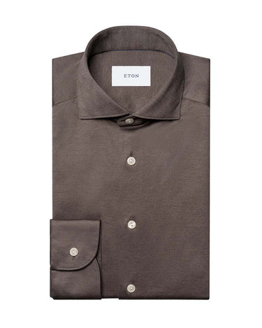 A folded Eton Filo di Scozia Jersey Slim Fit Brown Shirtwith a spread collar and a single cuff, featuring silver buttons and a white neck label with the brand name ETON.