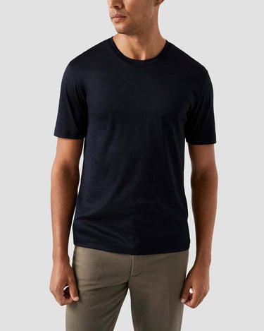 Man wearing a Eton Filo di Scozia T-Shirt, Navyand beige pants against a light gray background