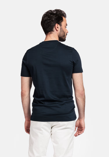 Man wearing a Giordano Luca Liquid Cotton Tee, Navy and white pants on a light gray background