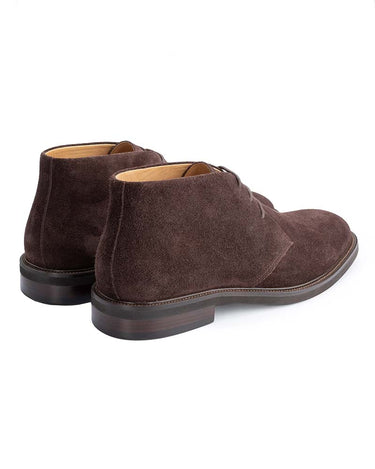 A pair of John White Wessex Suede Chukka Boots, Brown with dark brown laces and stacked low heels, shown from a three-quarters rear angle on a white background.