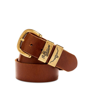 A R.M. Williams Drover Belt, Caramel with a polished gold-tone buckle and a matching keeper engraved with 'Phillips' and a winged logo, coiled on a white background.