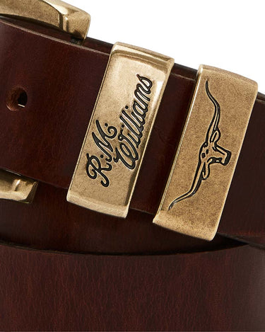 Close-up of aR.M. Williams Drover Belt, Mid Brown with brass-tone metal buckles, one engraved with 'R.M.