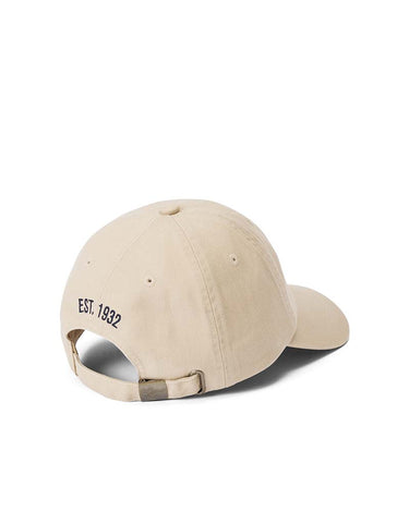 A R.M. Williams Longhorn Twill Cap, Ecru shown from a rear three-quarter angle on a clean white background, featuring the text 'EST. 1932' embroidered in black on the side and an adjustable strap at the back.