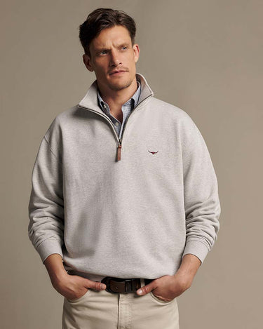 A man wearing a R.M. Williams Quarter Zip Sweat, Grey Marle with a small embroidered logo on the left chest, styled over a collared shirt and khaki pants against a neutral studio background.