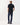 A man viewed from the back wearing a R.M. Williams Rod Pique Polo, Navyand dark blue jeans, standing against a plain light gray studio background.