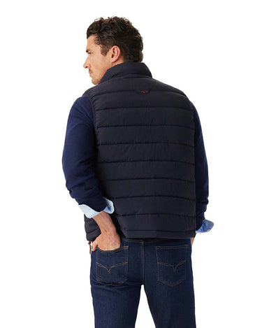 Man wearing a R.M. Williams Rydal Padded Gilet, Navy over a blue shirt on a white background