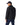 A man wearing a R.M. Williams Rydal Padded Jacket, Black, navy blue baseball cap, and dark blue jeans, shown from a side-back angle against a plain white background.