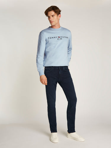 Man wearing a light blue Tommy Hilfiger sweatshirt and Tommy Hilfiger Denton Jeans, Blue Black on a white background