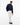 A man modeling a Tommy Hilfiger Dobby Cotton Shirt, Navy, worn over a navy button-down shirt, paired with off-white trousers and dark brown leather loafers, against a plain white studio background.