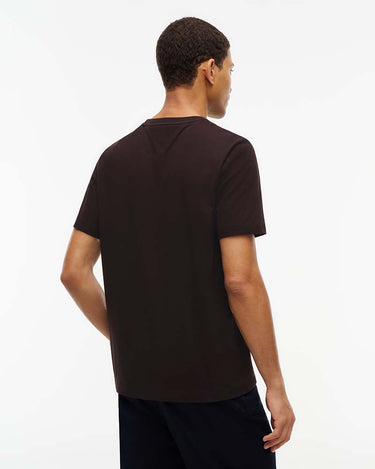 A man viewed from the back wearing a Tommy Hilfiger Flag Cotton T-Shirt, Brownand dark navy pants, set against a plain white studio background.