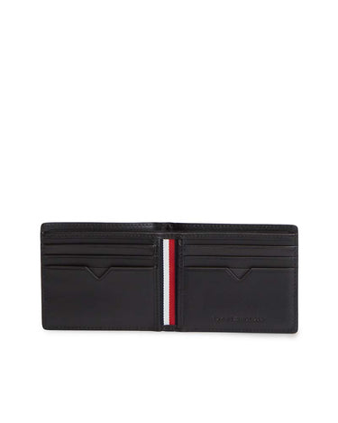 A Tommy Hilfiger Leather Bifold Wallet, Black shown open, featuring multiple card slots, a signature vertical red, white, and blue stripe down the center, and debossed branding on the lower right.