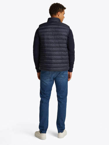 Man wearing a Tommy Hilfiger Packable Quilted Gilet, Navy and blue jeans on a white background
