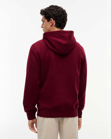 A man wearing a Tommy Hilfiger Peached Fleece Hoodie, Wine, shown from the back, paired with light beige trousers, against a plain white studio background.