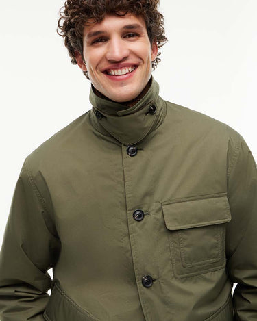 A smiling man wearing an olive green Tommy Hilfiger Corduroy Collar Padded Ripstop Barn Jacketwith dark buttons, photographed against a clean white studio background.
